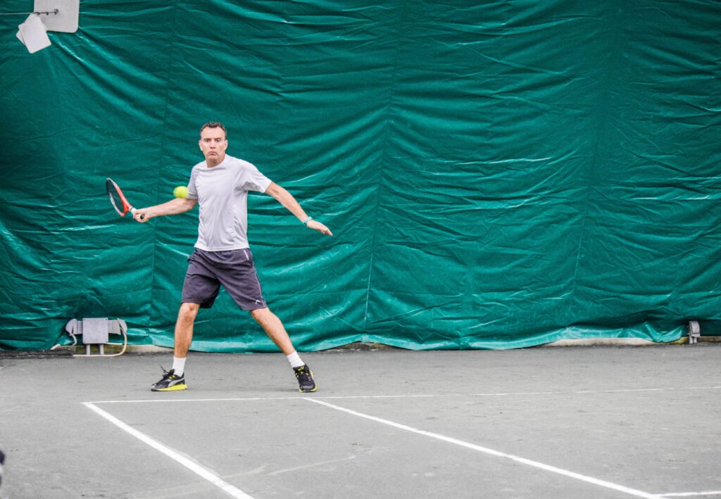 Ashley Heather hitting a forehand return on a tennis court.