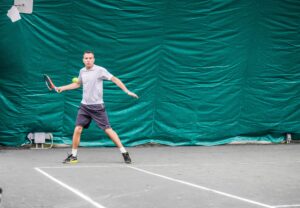 Ashley Heather hitting a forehand return on a tennis court.